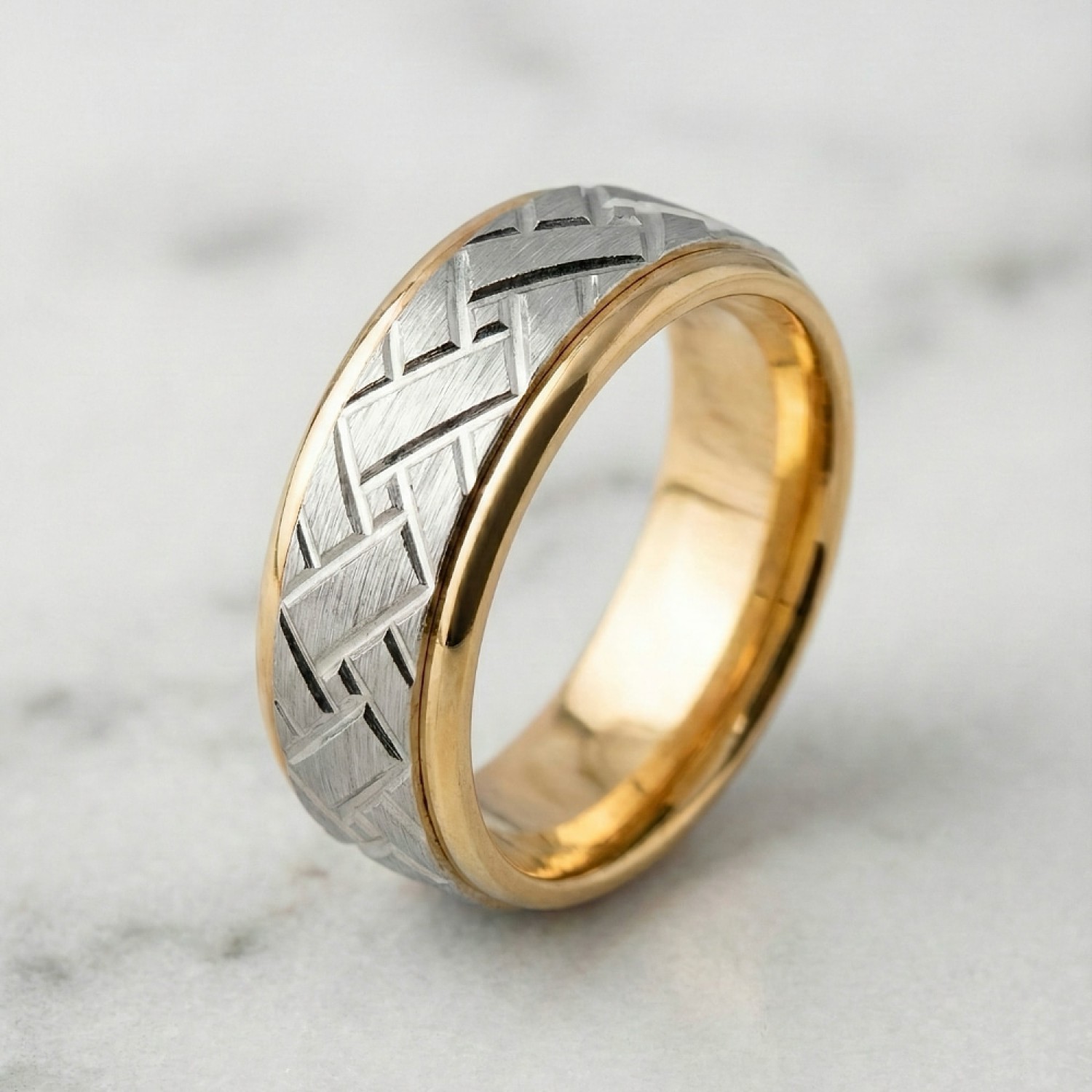 Close-up of a men's custom wedding ring. The band is 6mm wide with a two-tone construction. The outer rails and interior are high-polish 9k yellow gold. The center channel features a white gold insert with a matte satin finish and a deep-etched diagonal b