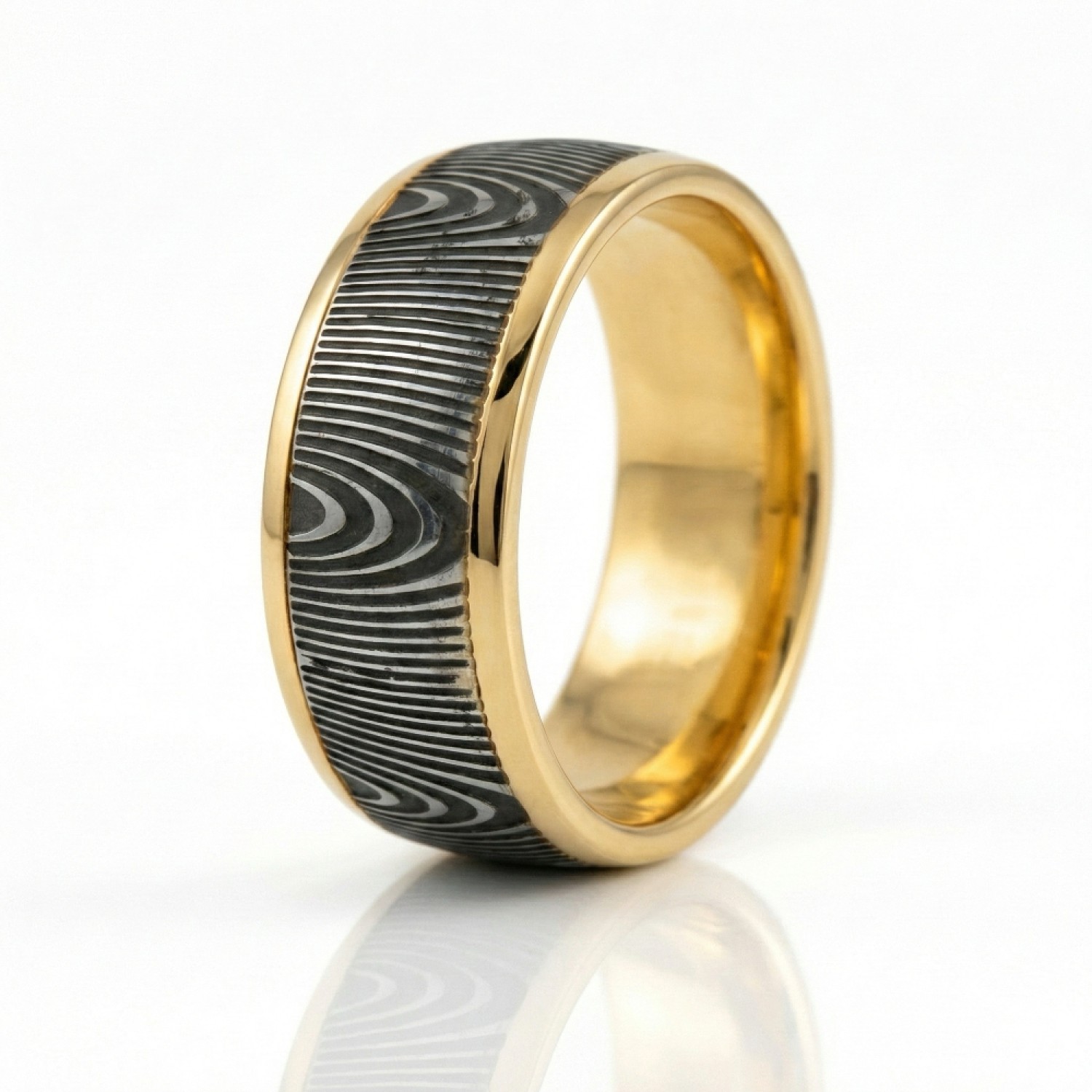 The Strata Wedding Ring: A polished yellow gold band featuring a central inlay of laser-carved black zirconium with a wavy woodgrain pattern, standing on a white background.